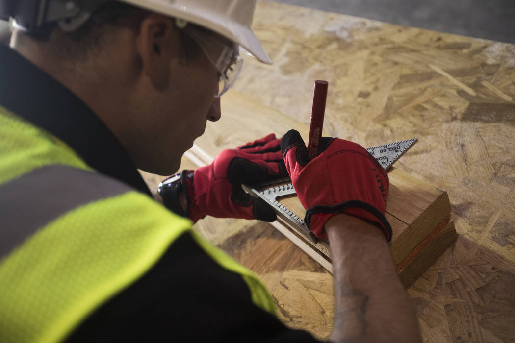 Brandon Lite takes measurements during a framing class for HomeAid WORKS, a program that teache ...