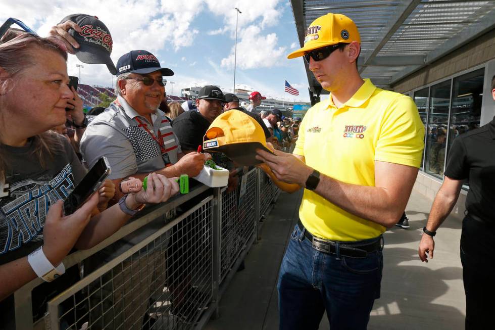 Driver Kyle Busch, right, gives autographs to fans prior to a NASCAR Cup Series auto race at IS ...