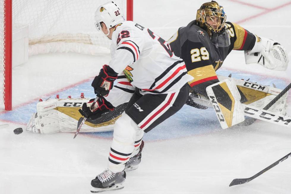 Chicago Blackhawks center Ryan Carpenter (22) watches a shot from teammate Kirby Dach (77) (out ...