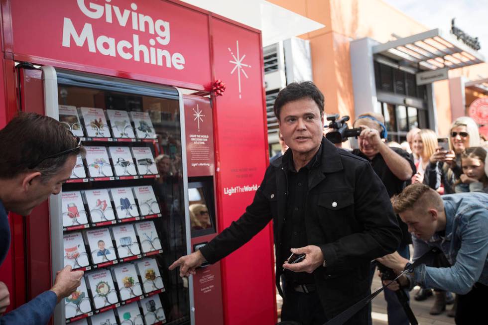 Donny Osmond purchases from the Giving Machine, a vending machine that offers different items f ...