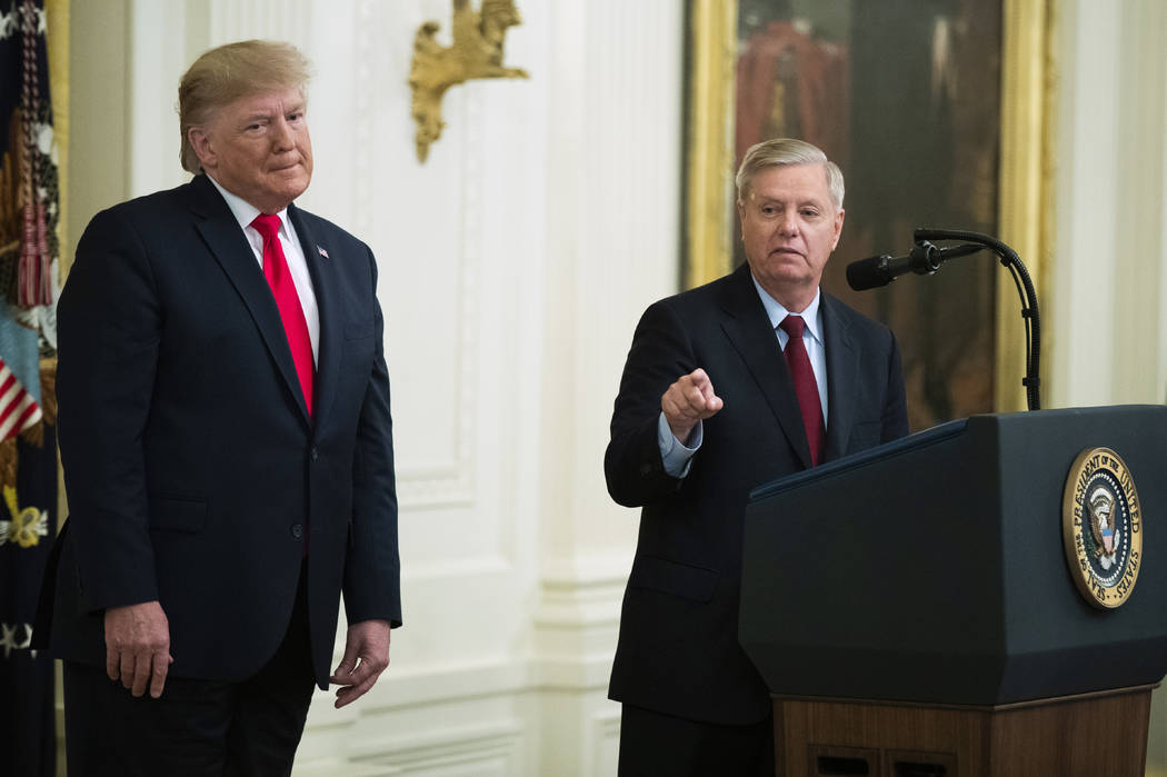 President Donald Trump listens to Sen. Lindsey Graham, R-S.C., speak during a ceremony in the E ...