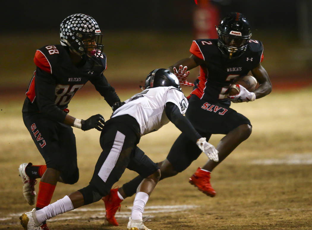 Las Vegas' Miles Davis (2) runs the ball under pressure from Palo Verde's Richard Gola-Collard ...