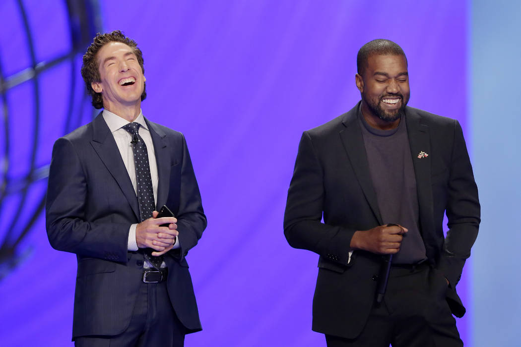 With their eyes closed for prayer, Joel Osteen, left, and Kanye West laugh as West makes a joke ...