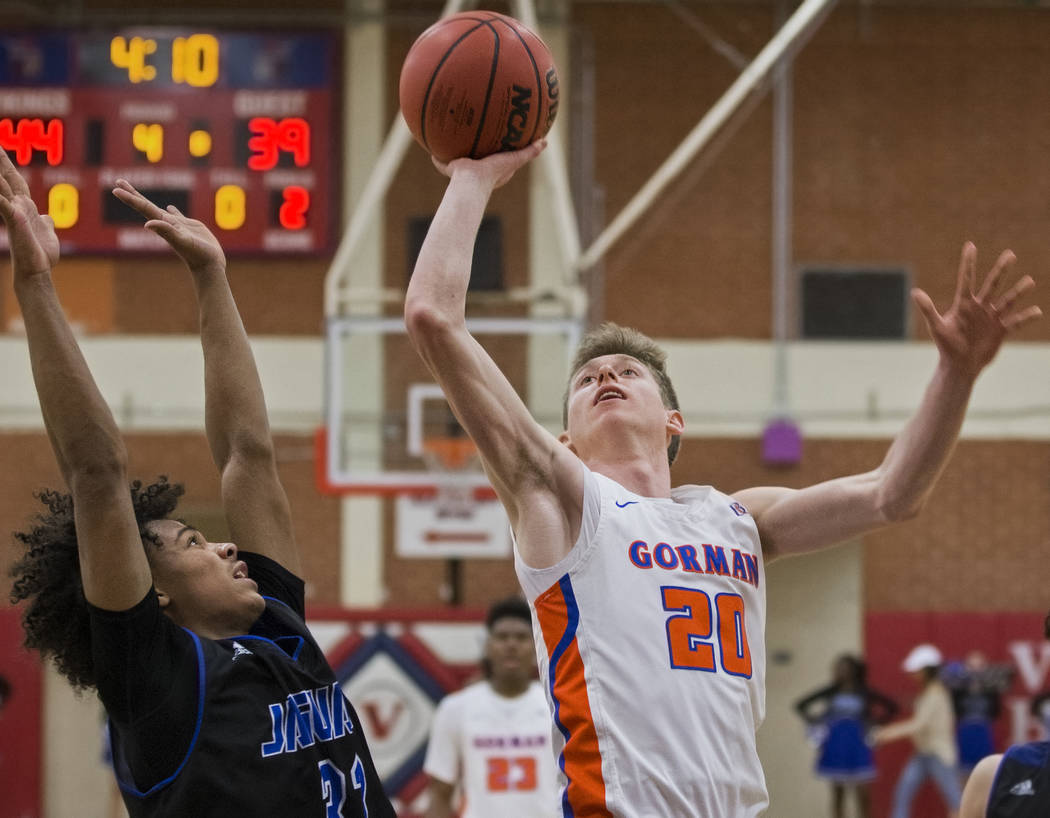 Bishop Gorman senior guard Noah Taitz (20) drives past Desert Pines freshman Jamir Stephens (3 ...