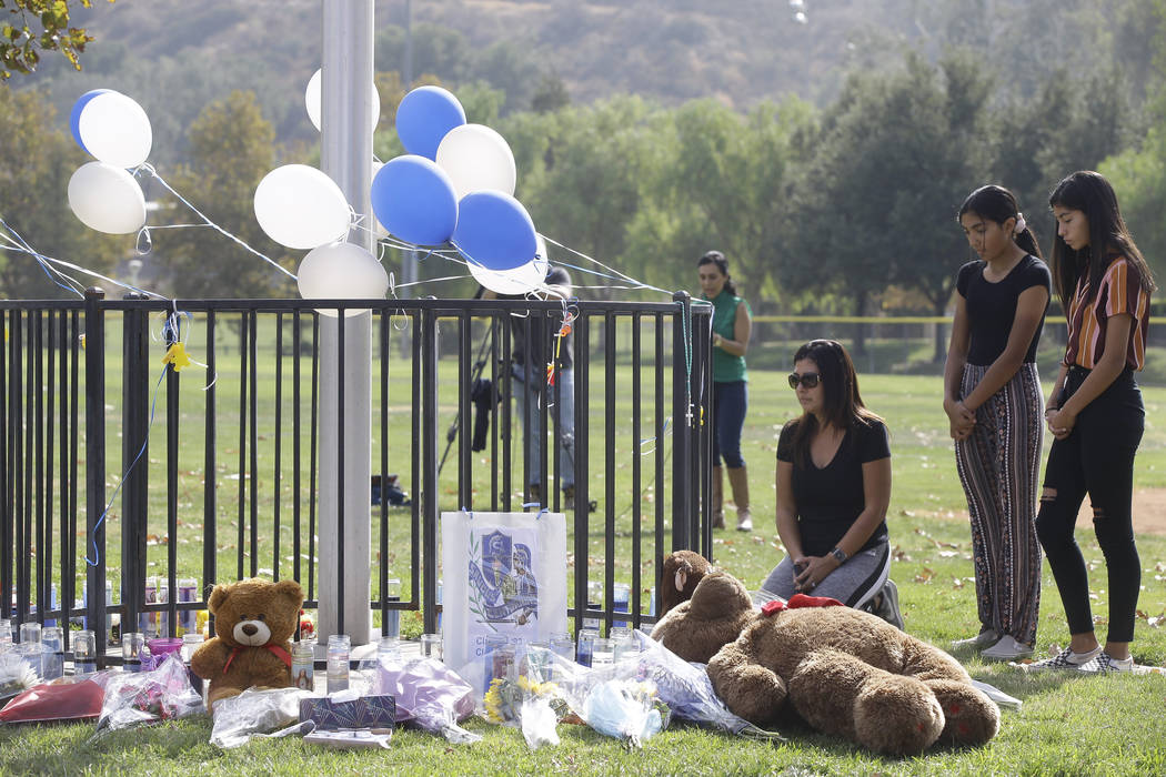 Parent Mirna Herrera kneels with her daughters Liliana, 15, and Alexandra, 16 at the Central Pa ...