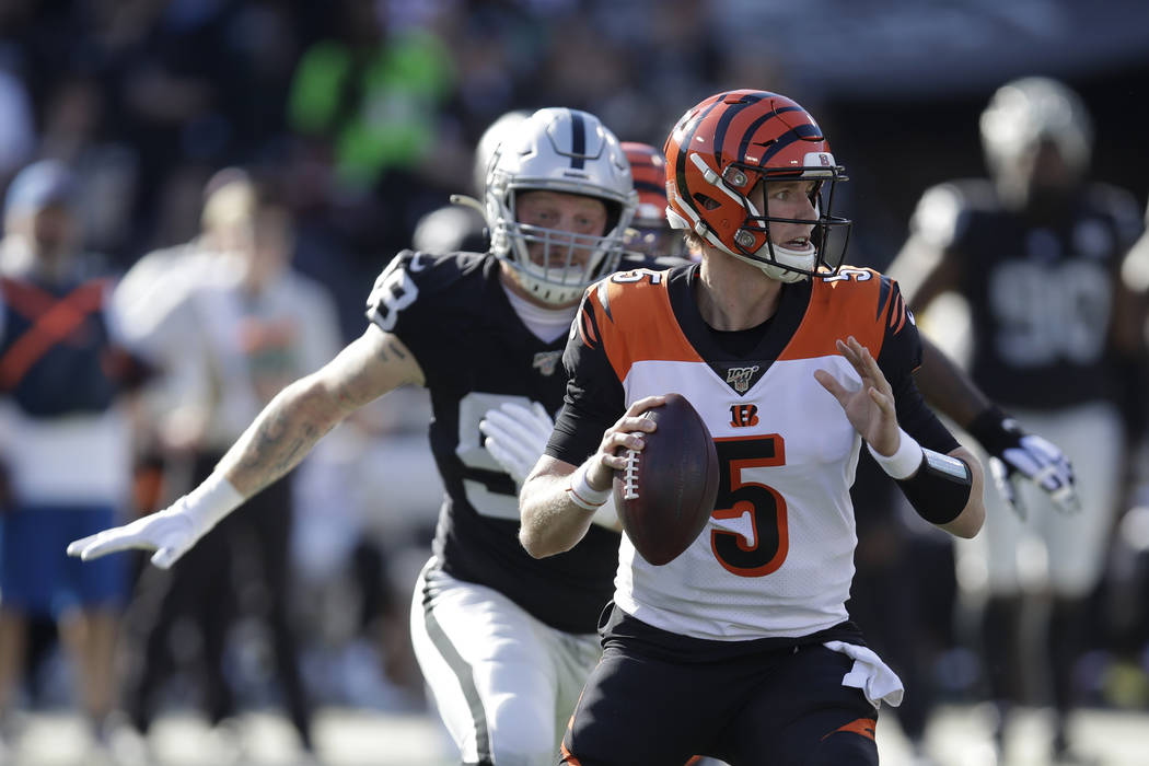 Cincinnati Bengals quarterback Ryan Finley and Oakland Raiders defensive end Maxx Crosby, left, ...