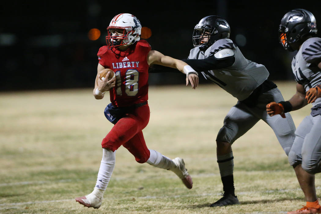 Liberty's quarterback Daniel Britt (18) is pushed out of bounds by Bishop Gorman's Dorian Stowe ...