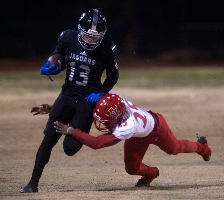 Desert Pines' Michael Jackson (13) runs with the ball as Arbor View's Adrian Bates (25) jumps t ...