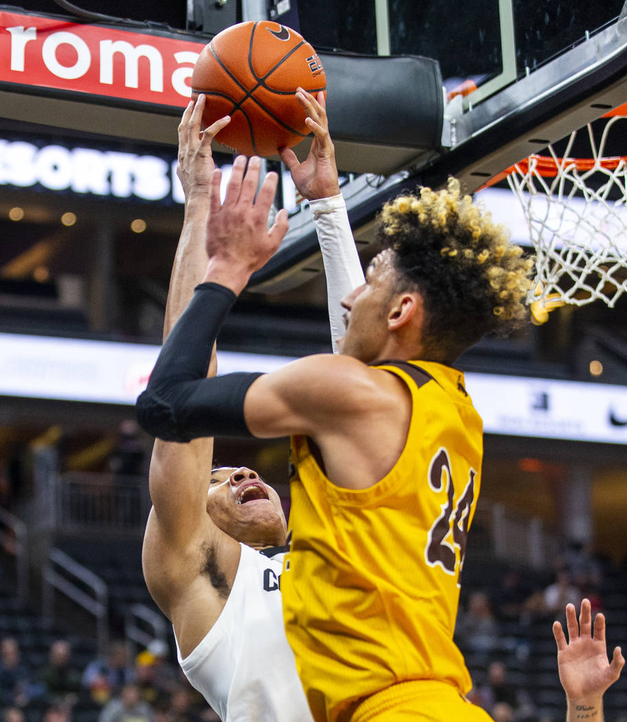 Colorado guard Tyler Bey (1, left) gets a hand on a loose ball with Wyoming guard Hunter Maldon ...