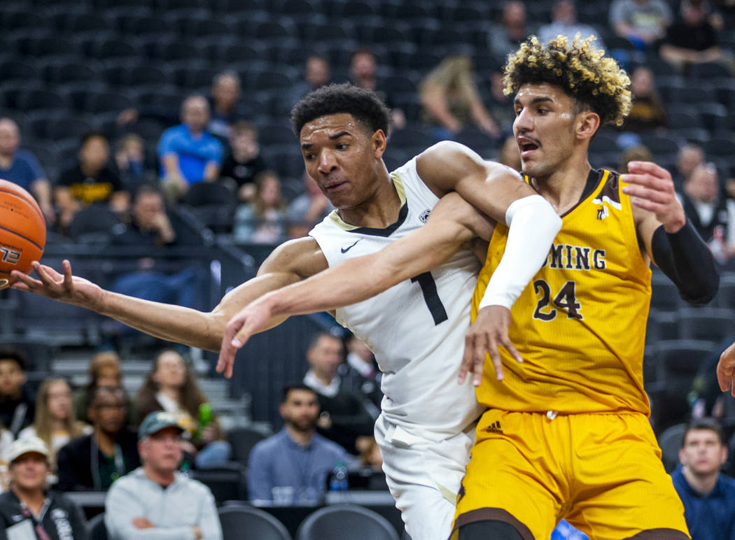 Colorado guard Tyler Bey (1, left) gets a hand on a loose ball with Wyoming guard Hunter Maldon ...