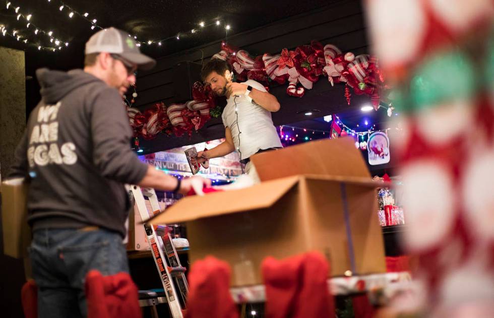 Garrett Pattiani, center, co-owner of Bright Light Holiday Company, works to hang lights at the ...