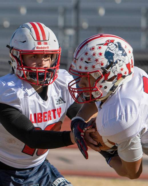 Liberty's quarterback Daniel Britt, left, hands the ball off to middle linebacker Zephaniah Mae ...