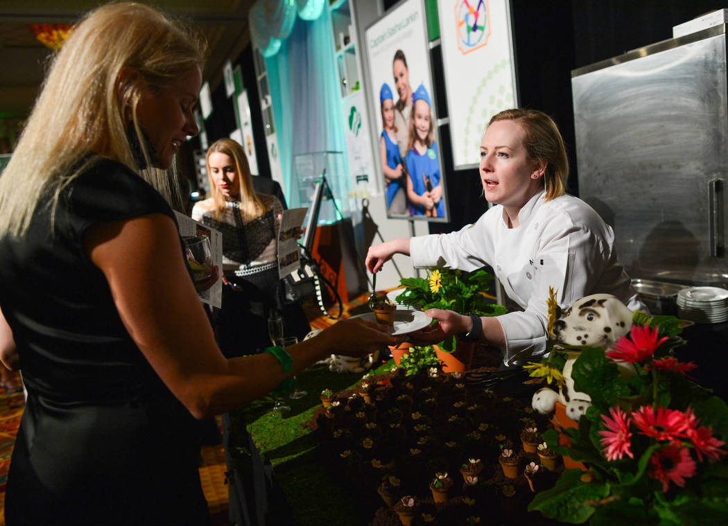 Chef Nicole Erle, right, from CUT by Wolfgang Puck, hands one of her tropical fruit dirt cups t ...