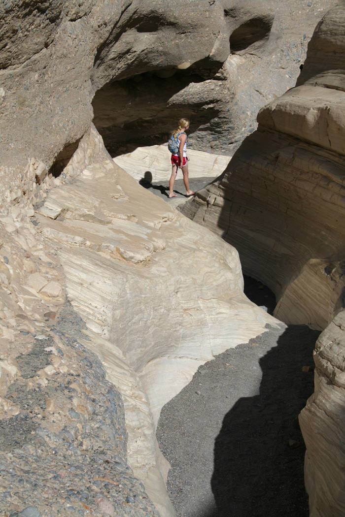 A hiker heads through a narrow section of Mosaic Canyon in Death Valley National Park, Californ ...