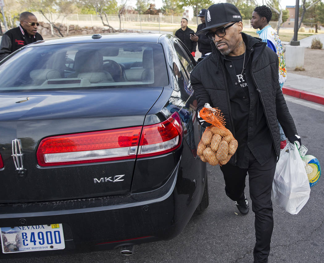Singer/songwriter Teddy Riley, right, delivers Thanksgiving dinners to a car during an event or ...