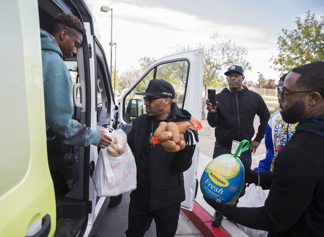 Sincere Basped, left, Teddy Riley and Will Roundtree load Thanksgiving dinners onto a bus durin ...