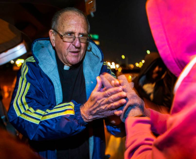 Father John McShane says a prayer for a woman in need during Giving Back Mondays on G Street an ...