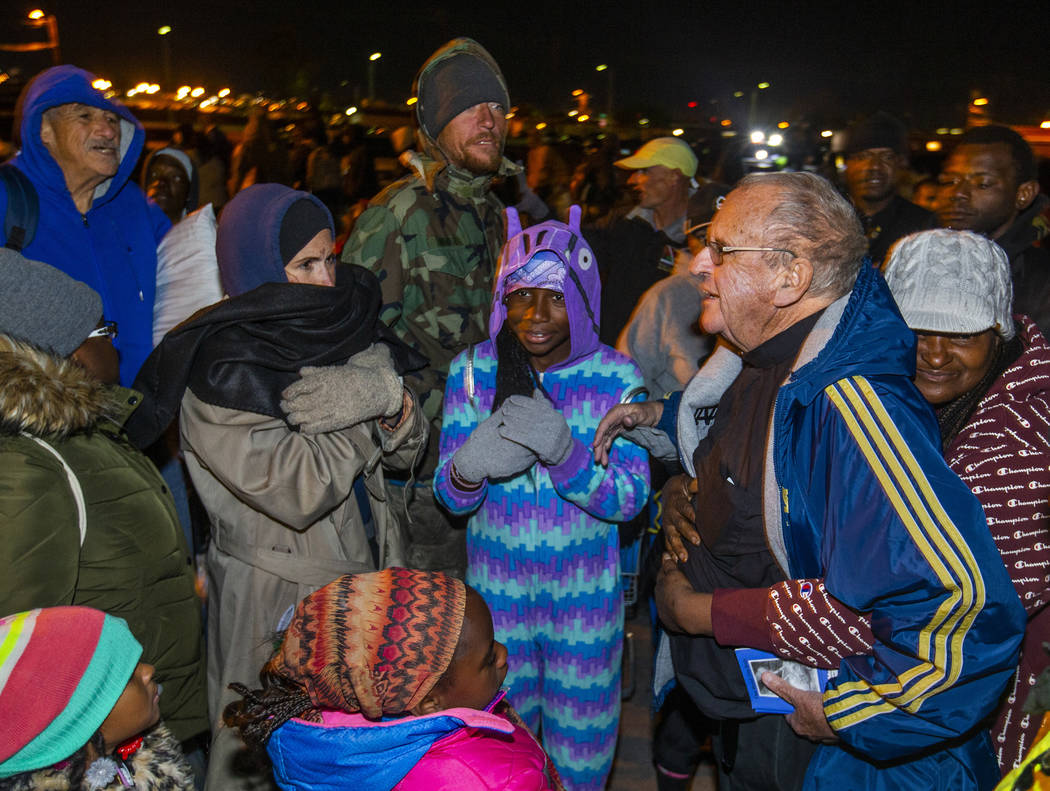 Father John McShane, right, receives a hug from behind as he offers prayers to those in need ga ...