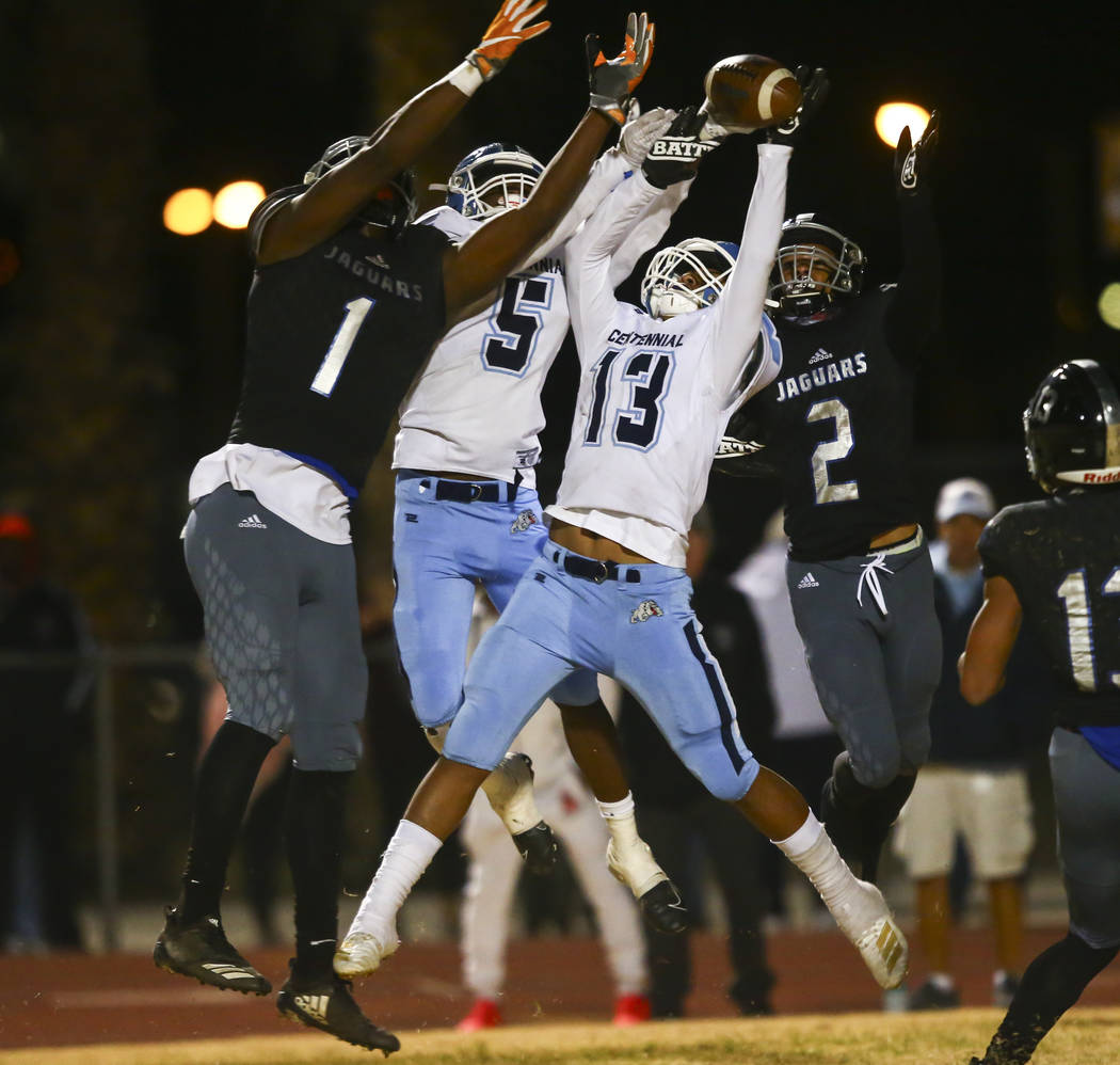 Centennial's Tyrone McCoy (5) and Ronaven Mokiao (13) break up a pass in front of Desert Pines' ...