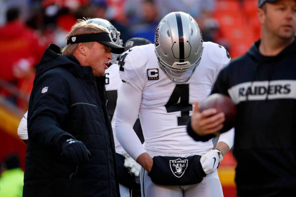 Oakland Raiders head coach Jon Gruden talks to quarterback Derek Carr (4) before an NFL footbal ...