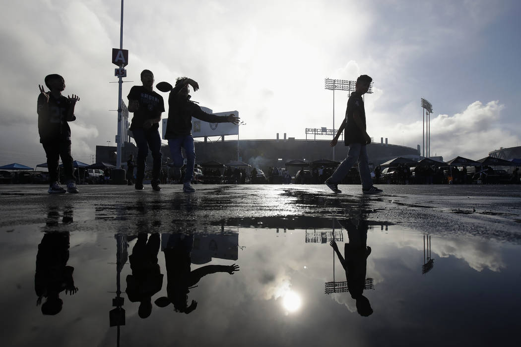 Fans play football while tailgating at RingCentral Coliseum before an NFL football game between ...