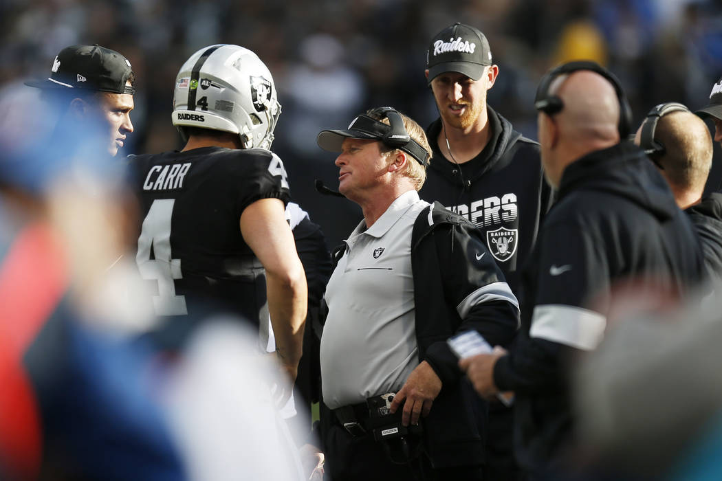 Oakland Raiders head coach Jon Gruden, center, talks with quarterback Derek Carr (4) during the ...