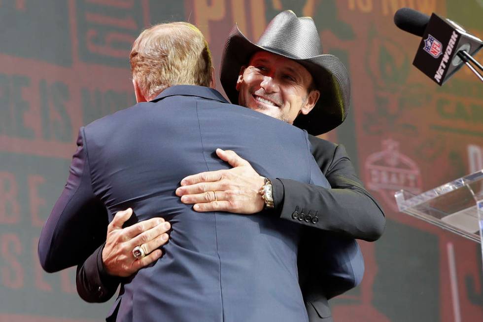 Country music star Tim McGraw hugs NFL Commissioner Roger Goodell ahead of the second round of ...