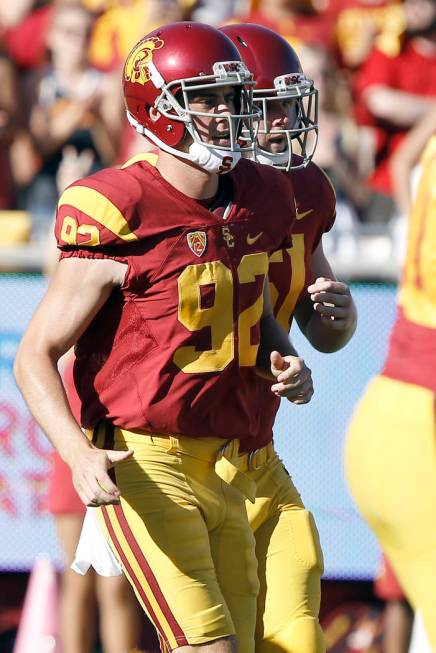 Southern California holder Wyatt Schmidt, left, runs on the field with blind long snapper Jake ...