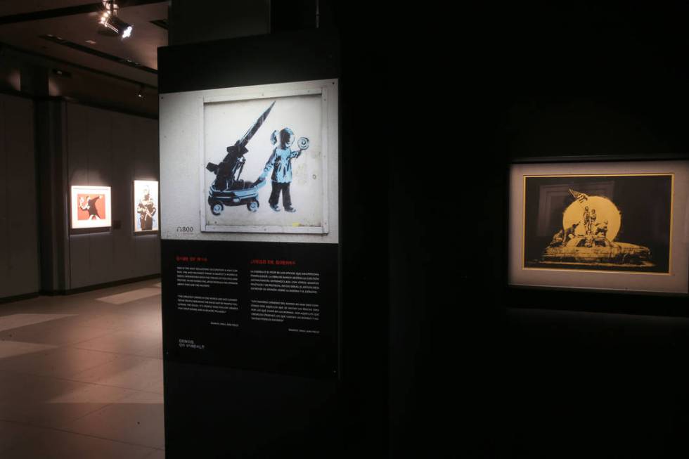 "Game of War," left, and "Flag (Gold)" on display in "Banksy: Genius o ...