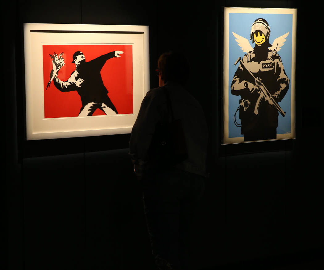Kim Thompon of Atlanta checks out "Rage, Flower Thrower," left, and "Flying Copper" in "Banksy ...