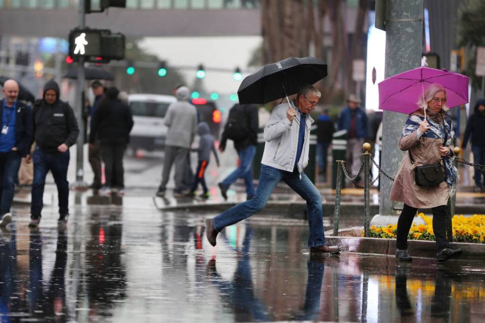 People walk a flooded intersection across from the Planet Hollywood casino-hotel in Las Vegas a ...