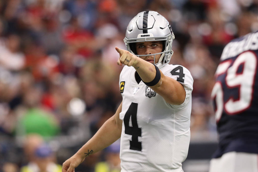 Oakland Raiders quarterback Derek Carr (4) points to a defender from the line of scrimmage as o ...