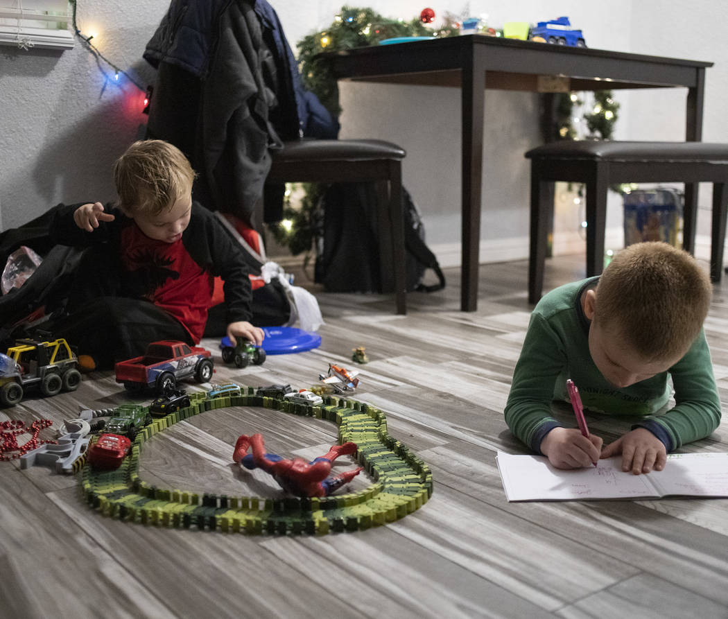 John Huebner, 2, left, plays with toy cars as Chase Huebner, 6, right, works on his schoolwork ...