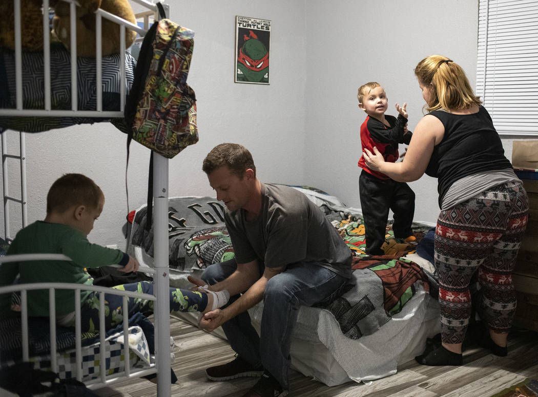 Dustin Huebner, second from left, helps his son Chase Huebner, 6, left, put on his pajamas as J ...