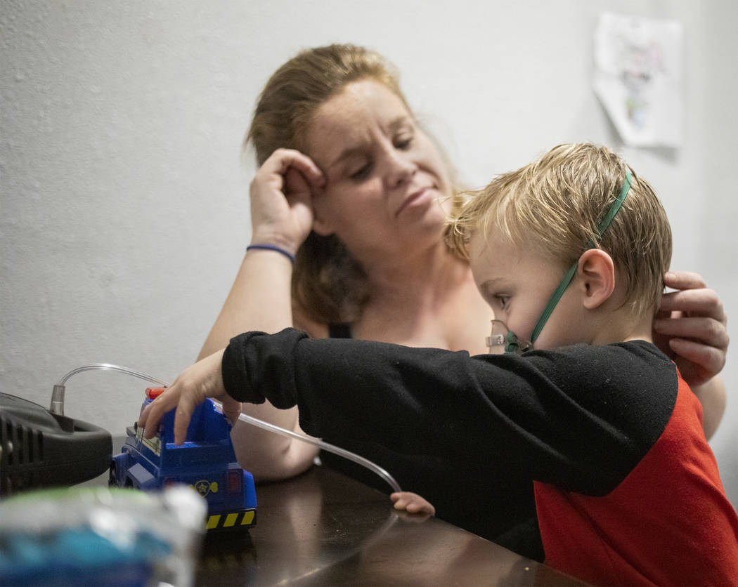 Joan Williams, left, watches as her son, John Huebner, 2, right, plays while receiving his lung ...
