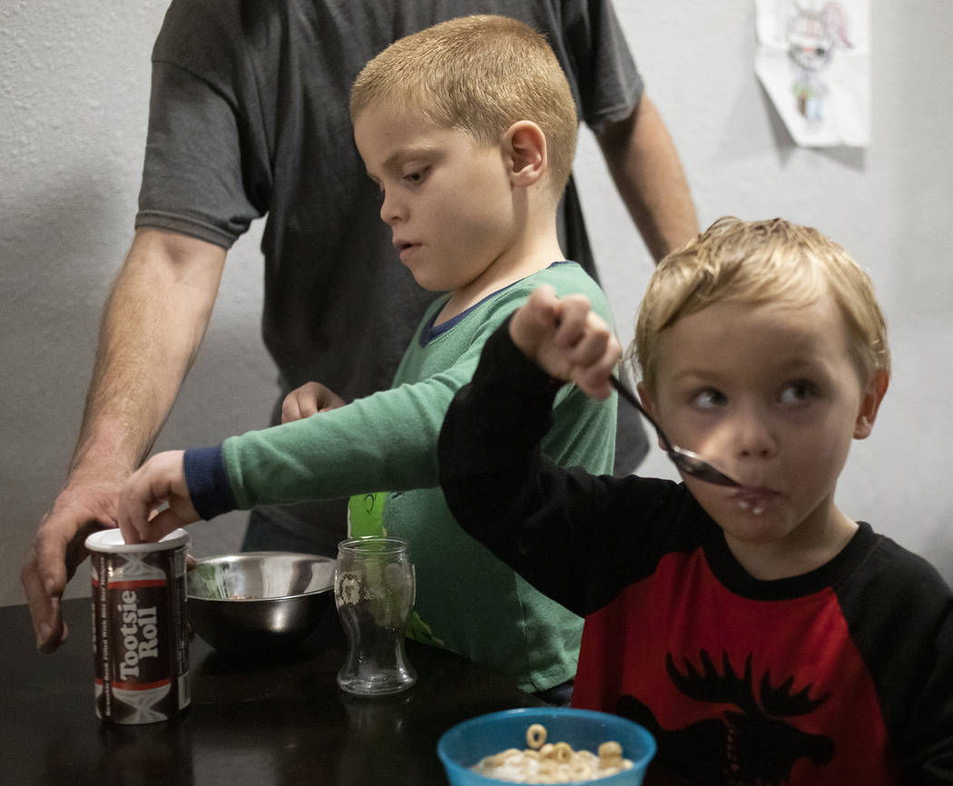 Dustin Huebner reaches to help his son, Chase Huebner, 6, left, fill his piggy bank as his othe ...