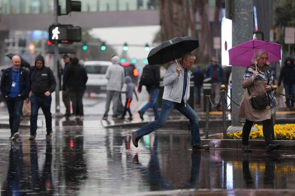 Some puddle-jumping is involved as people cross a flooded intersection across from Planet Holly ...