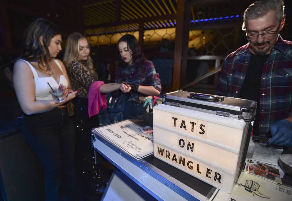 An attendee receives a temporary tattoo during the WNFR Party With Abandon at the Ling Ling Clu ...