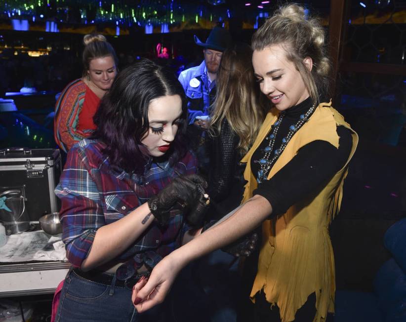 An attendee receives a temporary tattoo during the WNFR Party With Abandon at the Ling Ling Clu ...