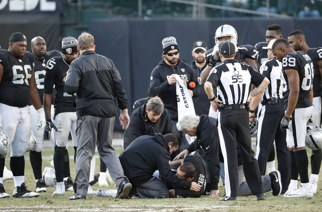 Oakland Raiders quarterback Derek Carr, bottom, is tended to after being injured against the In ...