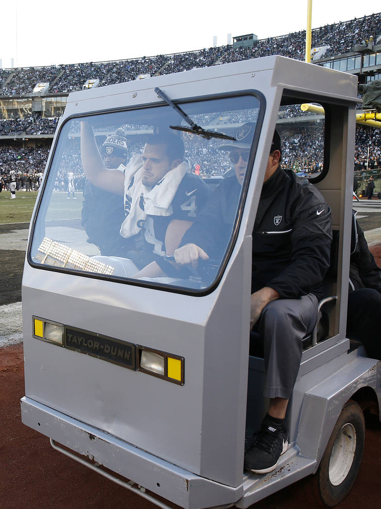 Oakland Raiders quarterback Derek Carr, left, is carted off the field after being injured again ...