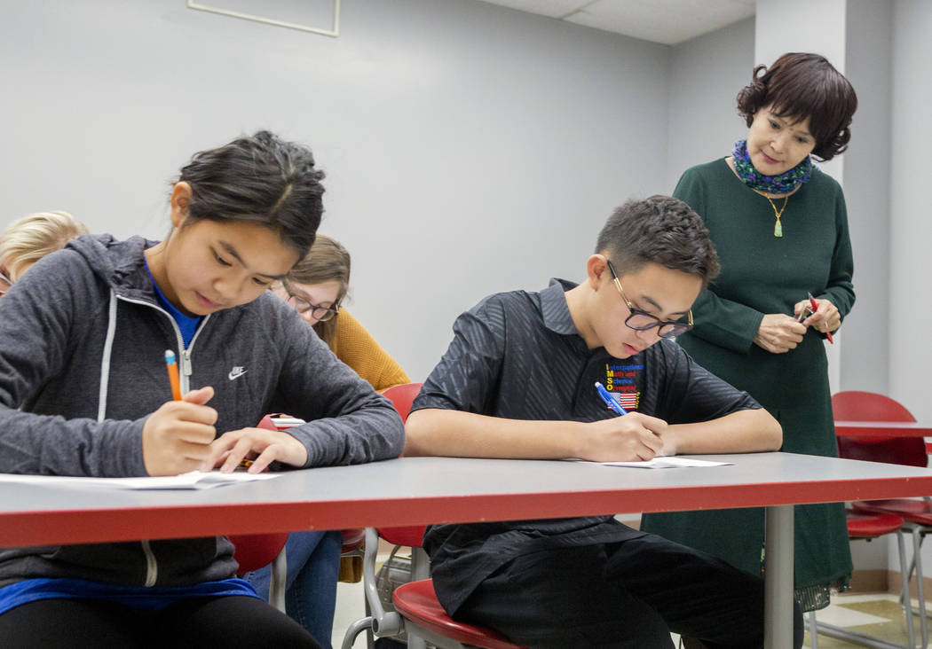 UNLV students Shenmei Wu, 13, left, and Shenlone Wu, 12, center, and professor Xiaoling Hays fo ...