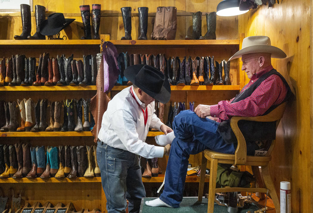M.L. Leddy's boot measurer Gabe Martinez of Fort Worth, Texas, left, prepares for custom made b ...