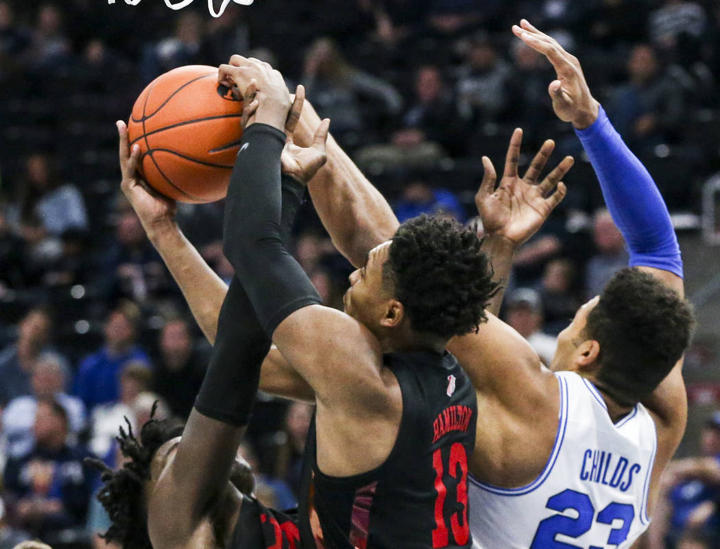 UNLV guard Bryce Hamilton (13) comes down with a rebound against BYU forward Yoeli Childs (23) ...