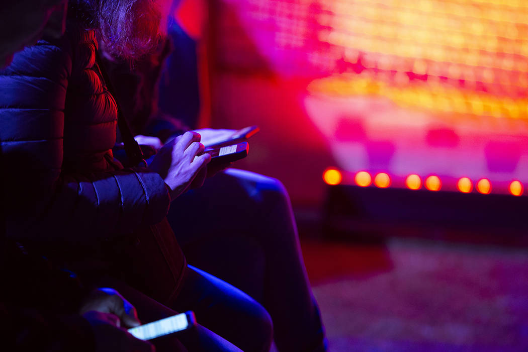 Festival-goers use their cell phones in one of the lounge areas as music plays on the stages on ...