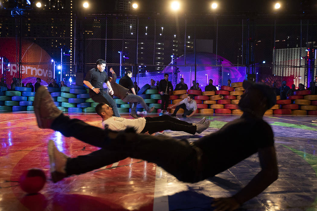 Participants in the dodgeball experience slip into the center of the court as they run to pick ...