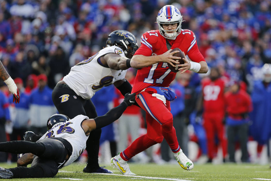 Buffalo Bills quarterback Josh Allen (17) is forced out of the pocket by Baltimore Ravens defen ...