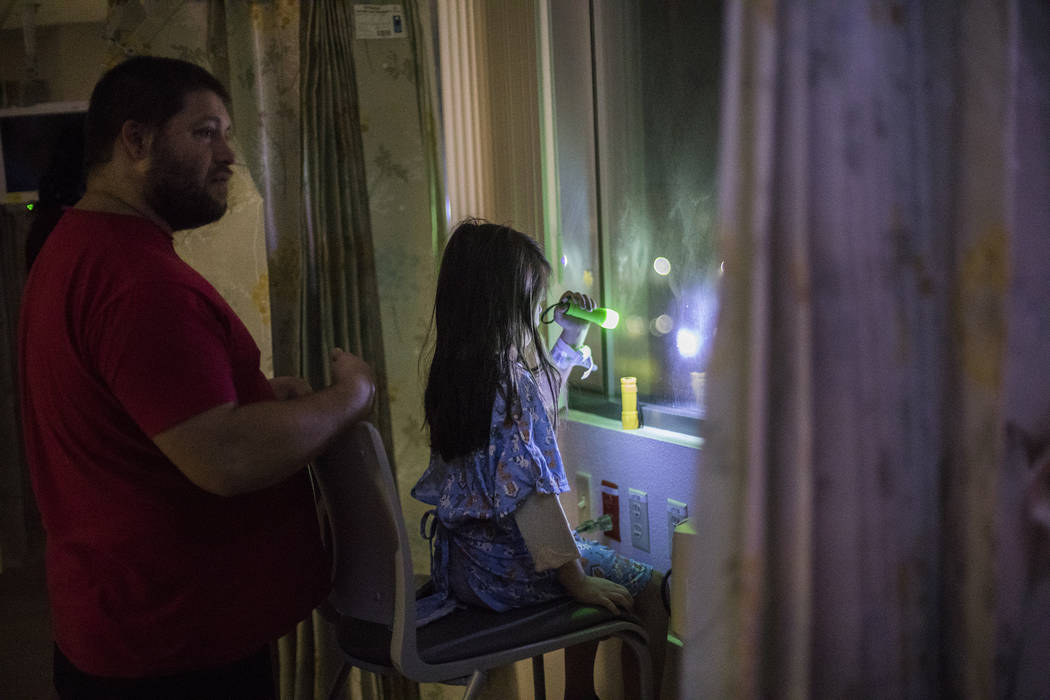 Alicia Langoria-Buffington, 5, in front of her dad David Langoria-Buffington, shines a flashlig ...