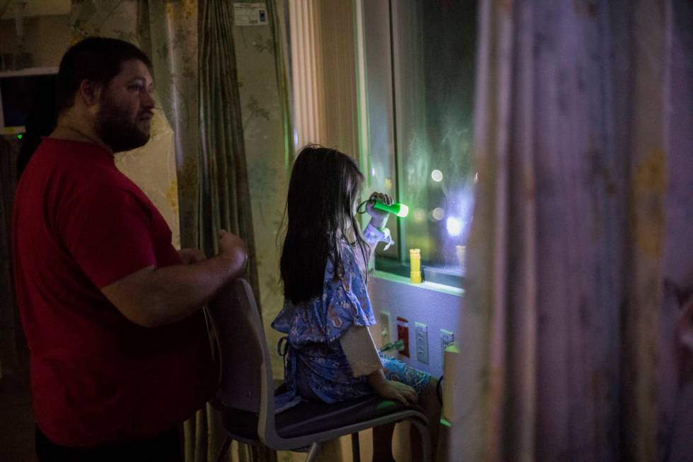 Alicia Langoria-Buffington, 5, in front of her dad David Langoria-Buffington, shines a flashlig ...