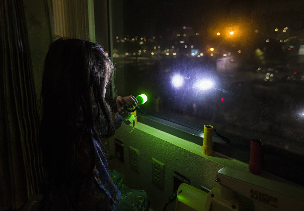 Alicia Langoria-Buffington, 5, shines a flashlight back at a crowd of people in the parking lot ...